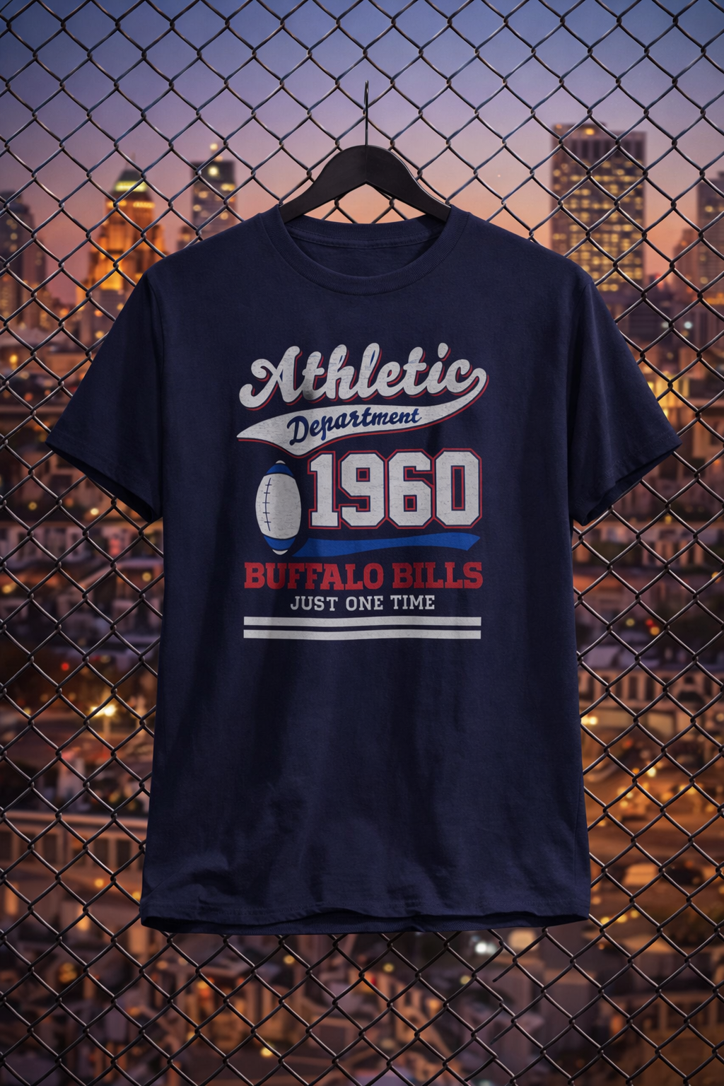 Navy blue t-shirt with 'Athletic Department 1960 Buffalo Bills Just One Time' text and graphic on a hanger against a cityscape background.