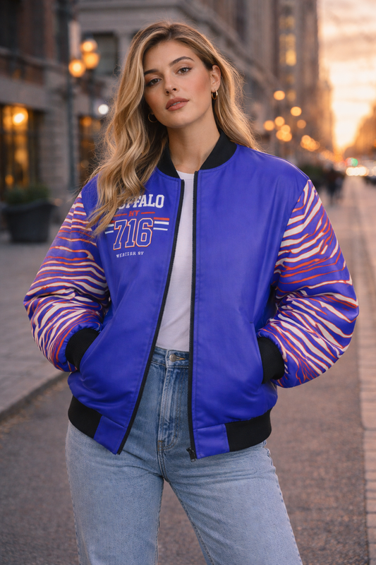 Woman wearing a blue bomber jacket with colorful sleeves on a city street.