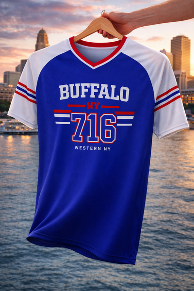 Blue and white t-shirt with 'Buffalo NY 716' text on a hanger against a cityscape background.