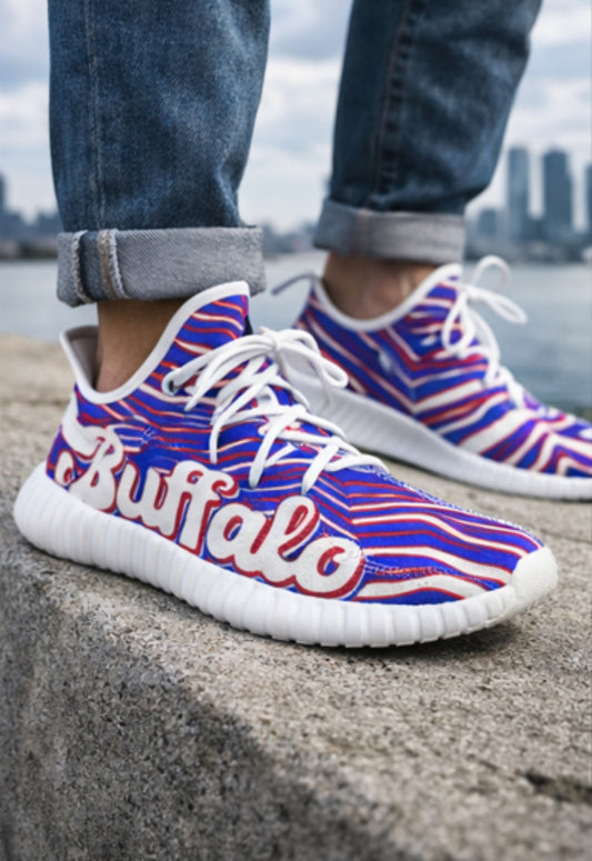 Sneakers with 'Buffalo' text and red, white, and blue pattern worn by a person on a concrete surface.