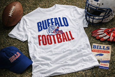 White t-shirt with 'Buffalo Football' text, surrounded by sports equipment on a grassy field.
