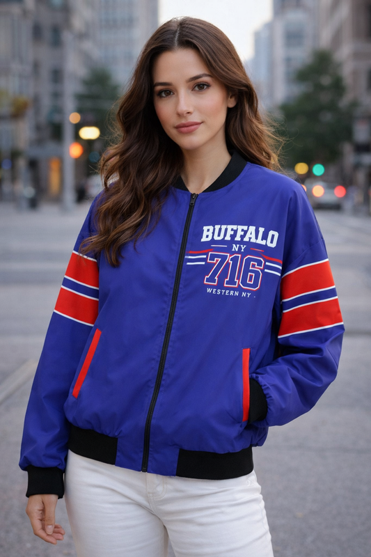 Woman wearing a blue bomber jacket with red and white accents on a city street.