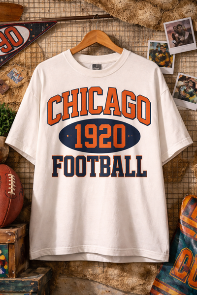 White t-shirt with 'Chicago 1920 Football' print on a wooden wall background.
