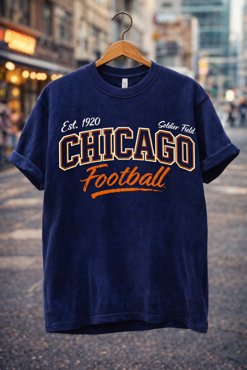 Navy blue t-shirt with 'Chicago Football' text on a hanger against a city street background
