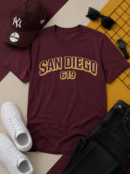 Maroon t-shirt with 'San Diego 619' text, white sneakers, black pants, sunglasses, and a cap on a patterned surface.