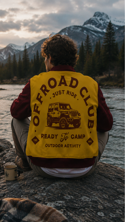 Person wearing an 'Offroad Club' vest sitting by a campfire with mountains in the background