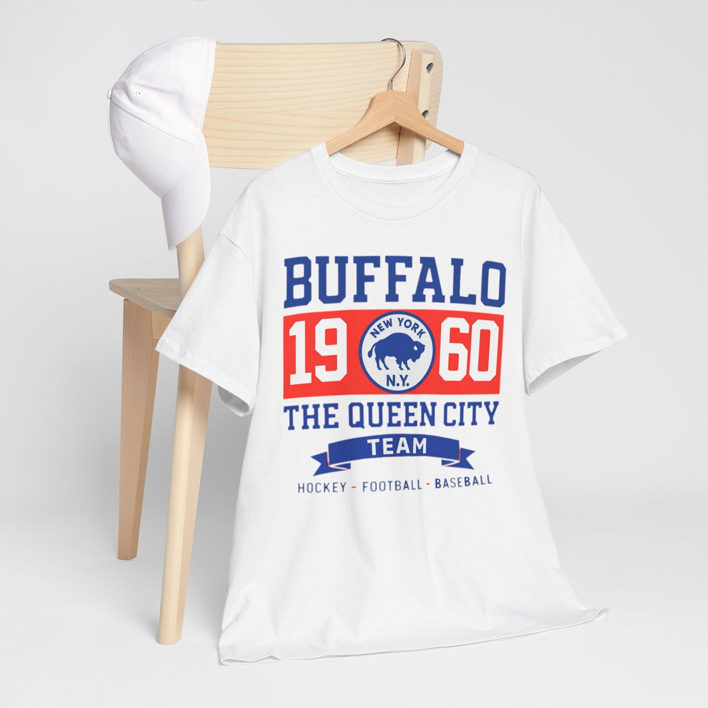 White t-shirt with 'Buffalo 1960 The Queen City Team' text on a wooden chair against a white background