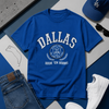 Blue 'Dallas' t-shirt with jeans, sneakers, and a cap on a blue and gray surface