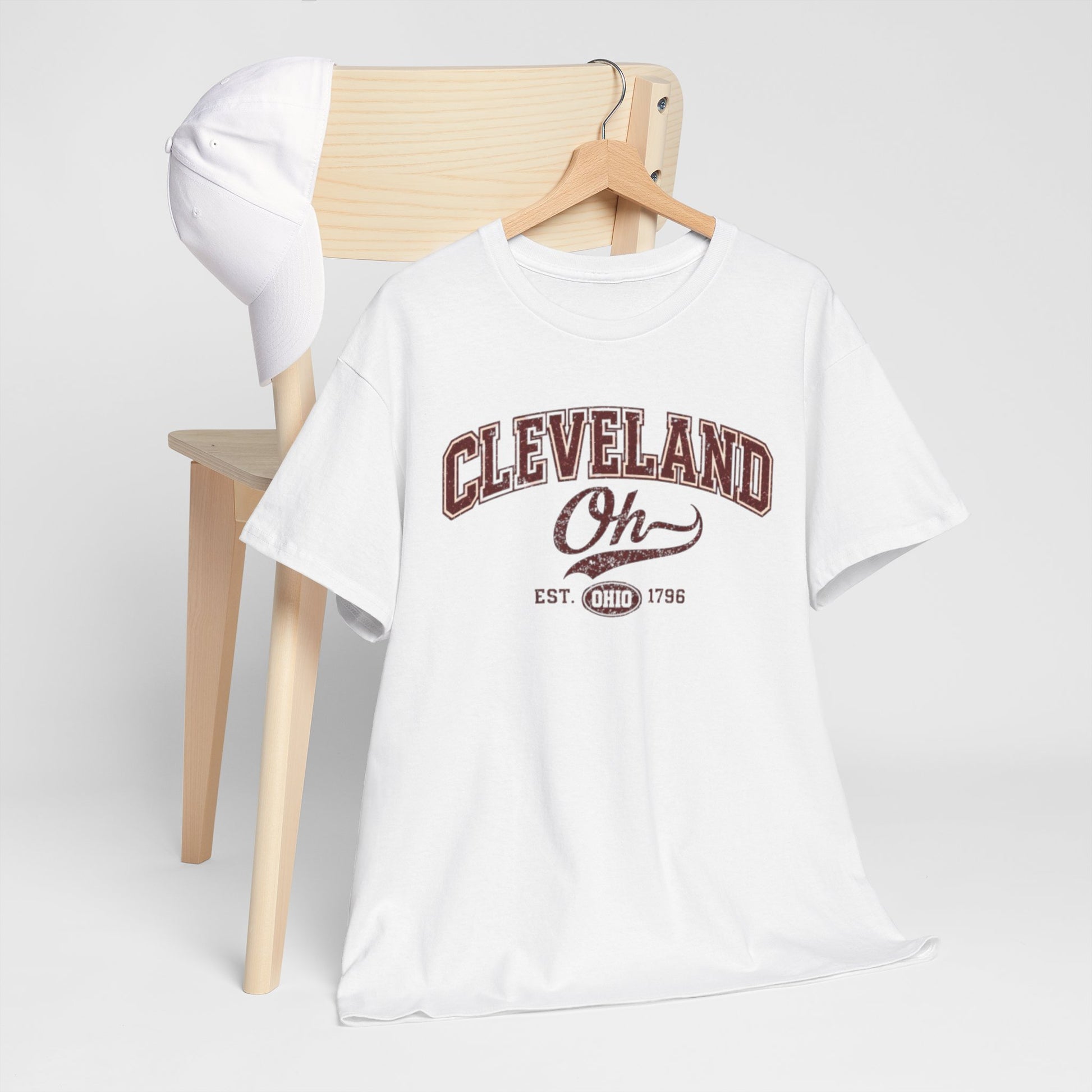 White t-shirt with 'Cleveland Oh' text on a wooden chair against a white background
