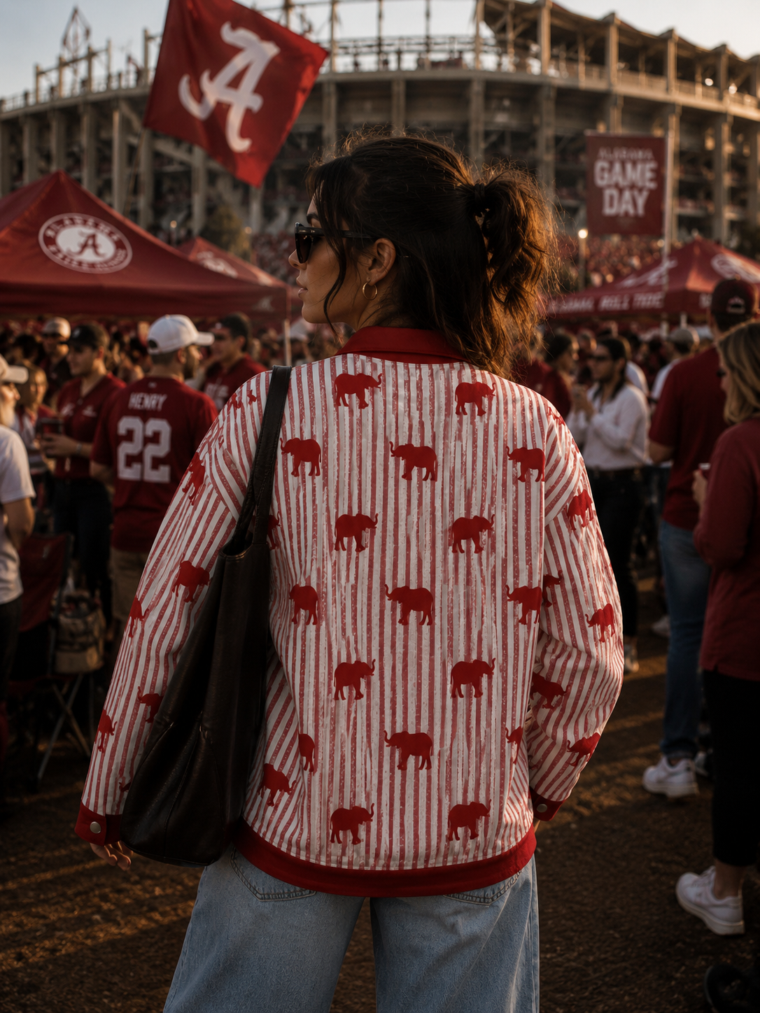 Person wearing a sweater with red elephant patterns at a sports event, surrounded by people and tents.
