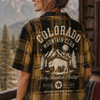 Person wearing a 'Colorado Mountain Club' plaid shirt with a scenic background