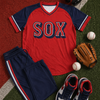 Baseball-themed outfit with red and navy 'SOX' jersey, pants, shoes, baseballs, and a glove on a baseball field.