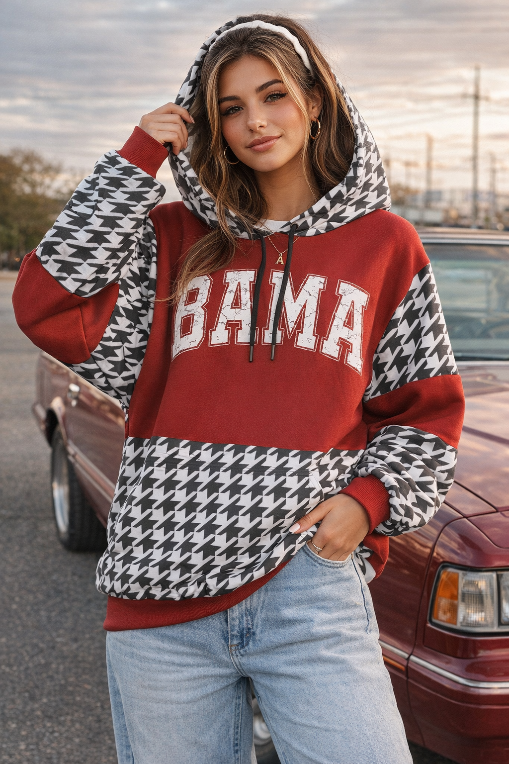 Person wearing a red and black patterned hoodie with 'BAMA' text, standing in front of a vintage car.