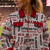 Woman in a patterned jacket at a sports event with a stadium in the background