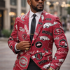 Man wearing a red patterned blazer with logos, standing on a city street.
