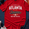 Red t-shirt with 'Atlanta Champion' text on a blue surface with sneakers and a jacket.