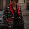 Man wearing a colorful jacket with logos and sunglasses, standing next to a car.