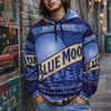 Person wearing a Blue Moon hoodie leaning against a brick wall with street art.
