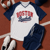 Boston Baseball-themed shirt with navy sleeves, shorts, sneakers, headphones, and a cap on a brown surface.