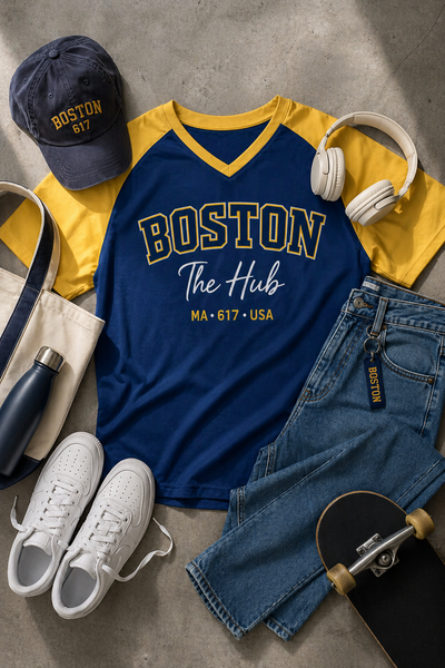 Blue and yellow 'Boston The Hub' t-shirt with accessories on a concrete surface
