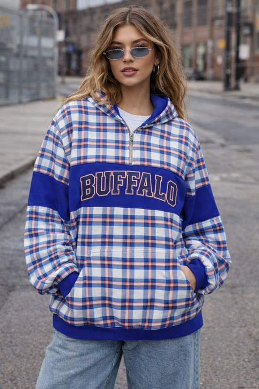 Person wearing a plaid shirt with 'Buffalo' text on a city street