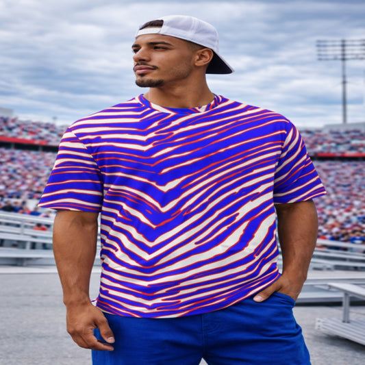 Man wearing a colorful striped shirt and blue pants standing in an outdoor setting with a cloudy sky.