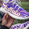 Colorful sneaker with 'Buffalo' text held by a hand outdoors.