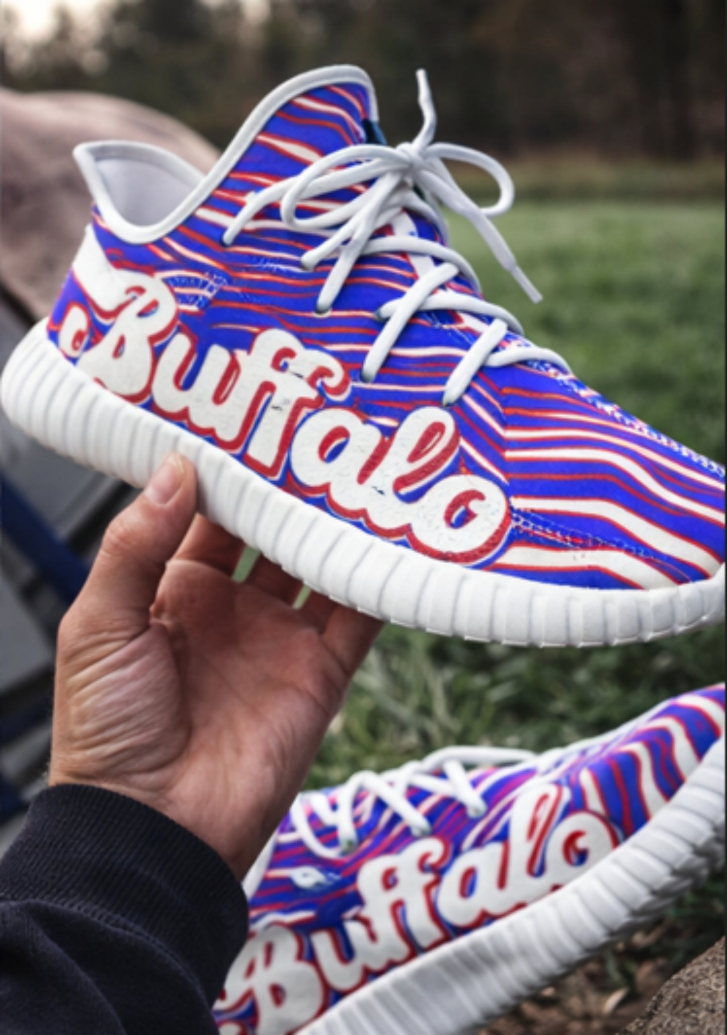Colorful sneaker with 'Buffalo' text held by a hand outdoors.