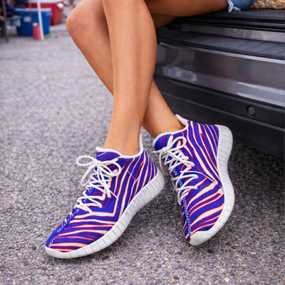 Buffalo bills sneakers. Person wearing blue and pink striped sneakers on a street.