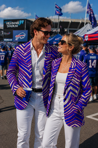 Two people in matching blue and white striped blazers at a sports event.