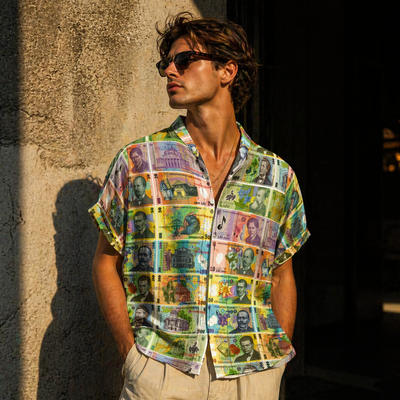 Man wearing a colorful shirt with international currency designs against a textured wall.