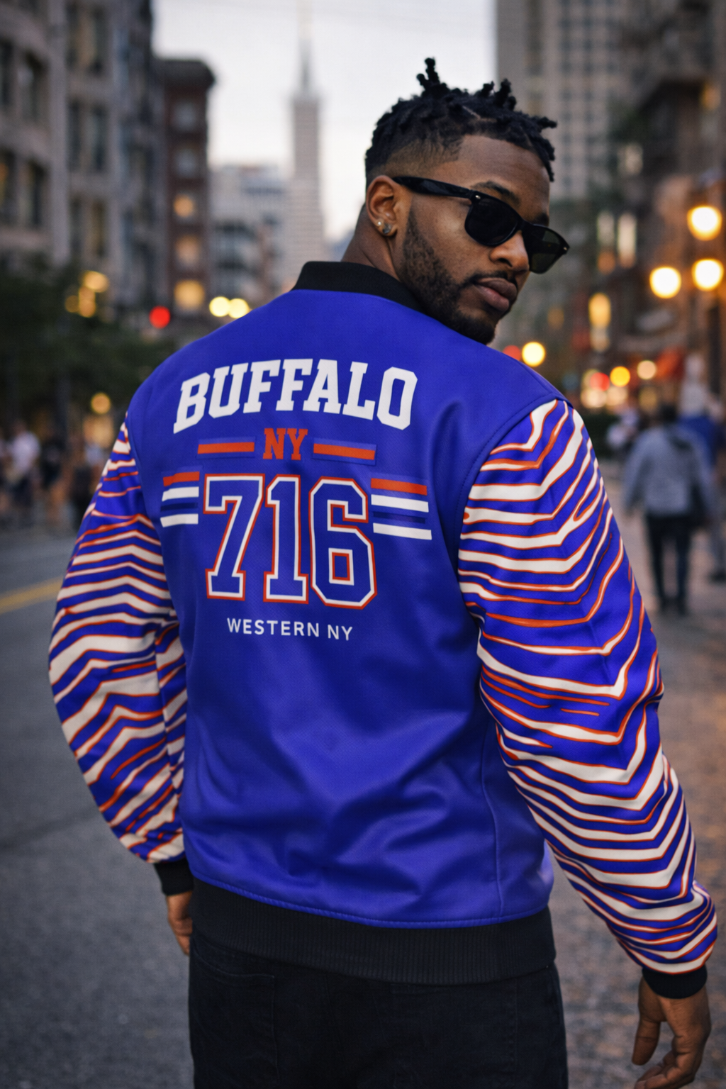 Man wearing a blue letterman jacket with 'Buffalo NY 716' on a city street.