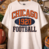 White t-shirt with 'Chicago 1920 Football' print on a wooden wall background.