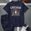 Navy blue t-shirt with 'Chicago Midwest Athletics Society' design, dark pants, white sneakers, basketball, and headphones on a gray surface.