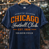Navy blue t-shirt with orange and white text on a hanger against a blurred background