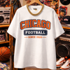 White t-shirt with 'Chicago Football Since 1920' text on a hanger in a store setting.