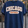 Navy blue t-shirt with 'Chicago Football' text on a hanger against a blurred background