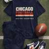 Navy t-shirt with 'Chicago Football' text, navy pants, blue sneakers, football, and headphones on grass.