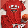 Red 'Chicago Hoops' t-shirt with shorts, sneakers, and a basketball on a textured surface.