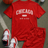 Red 'Chicago Men in Red' t-shirt with shorts, basketball, sneakers, and headphones on a textured surface.