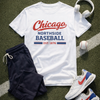 White t-shirt with 'Chicago Northside Baseball' text, navy shorts, white sneakers with red and blue accents, and a baseball on a grassy field.
