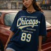 Person wearing a navy blue 'State University Chicago' t-shirt with a cityscape in the background.