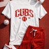 White t-shirt with 'Cubs' print, red shorts, white sneakers, and headphones on a red textured surface.