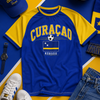 Blue and yellow 'Curacao' themed shirt with accessories on a blue and yellow background
