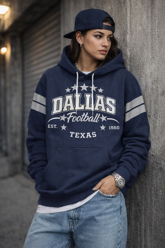 Person wearing a navy blue 'Dallas Football' hoodie leaning against a wall.