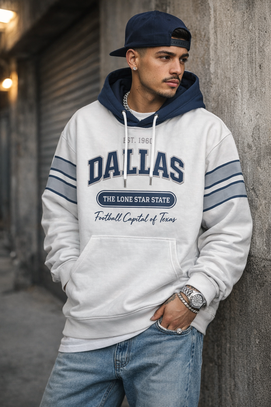 Man wearing a 'Dallas' hoodie leaning against a wall.