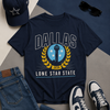 Navy blue t-shirt with 'Dallas Lone Star State' design, accompanied by a cap, jeans, sneakers, and sunglasses on a geometric background.