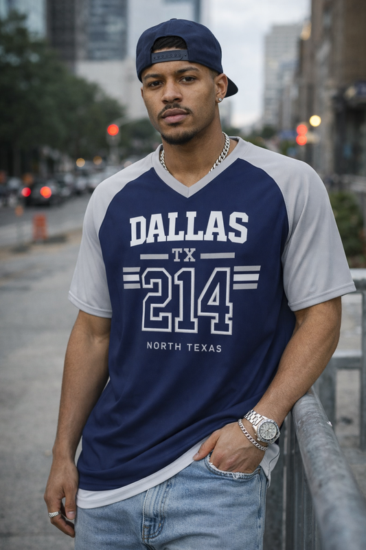 Man wearing a blue and gray 'Dallas TX 214' t-shirt on a city street.