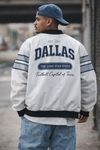 Person wearing a white jacket with 'Dallas' text, standing outdoors.