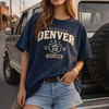 Woman wearing a 'Colorado Denver' t-shirt standing in front of a vehicle.